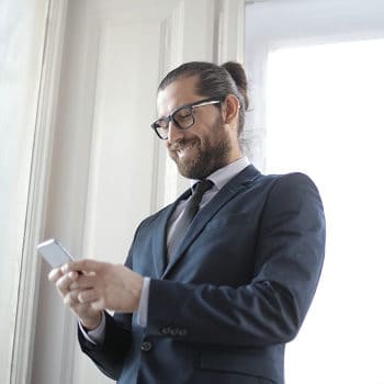 Businessman smiling at smartphone indoors.